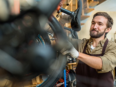 Professional repairman with spanner fixing detail of bicycle wheel